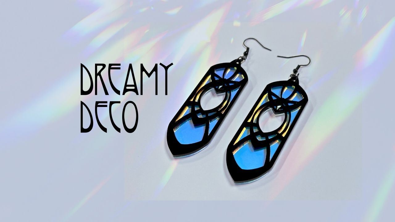 Iridescent and black earrings on a reflective surface with 'Dreamy Deco' branding.