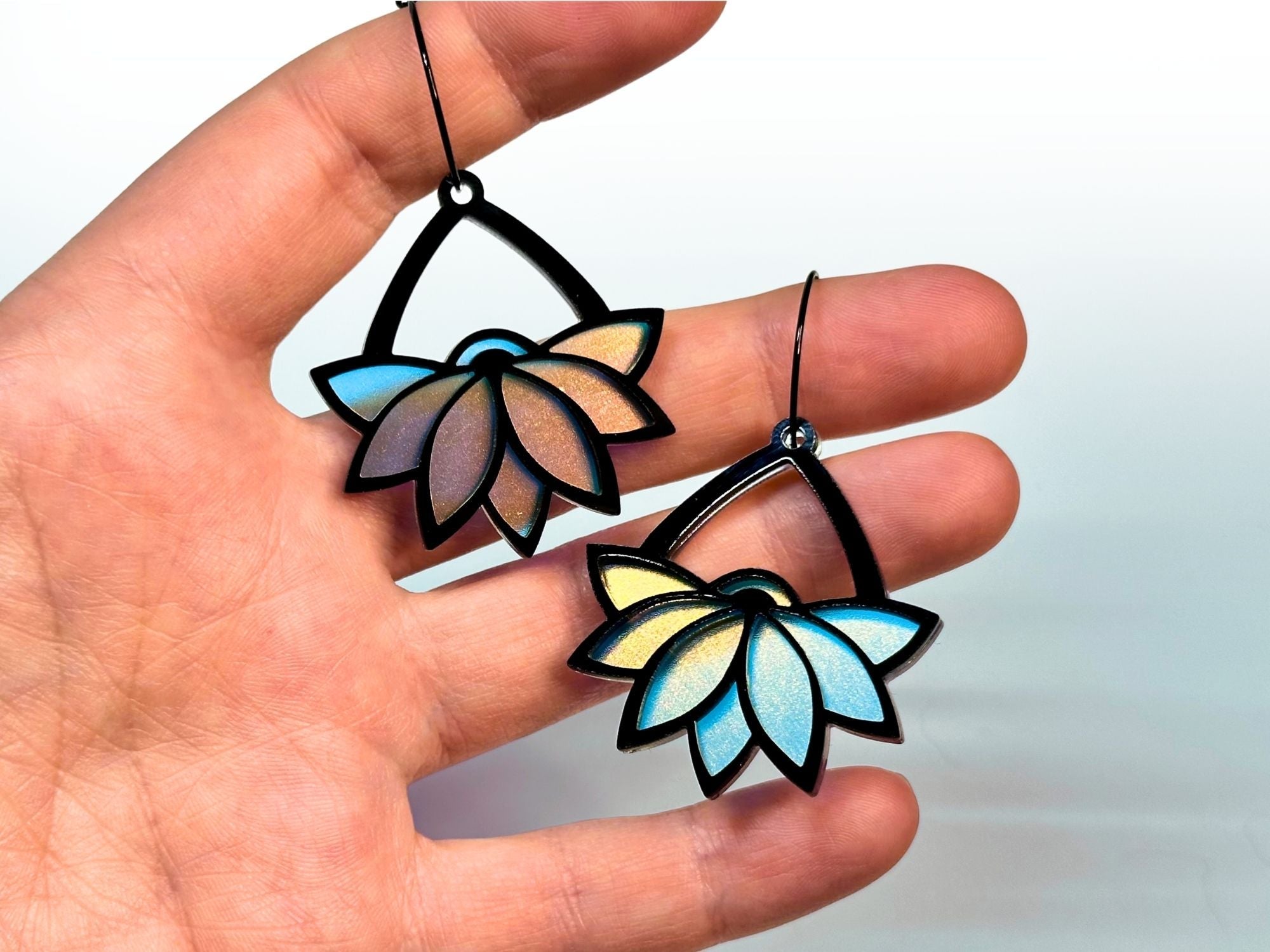Hand holding Obsidian lotus hoop earrings for size reference