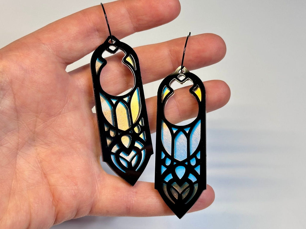 Hand holding black and iridescent Arwen statement earrings for size reference