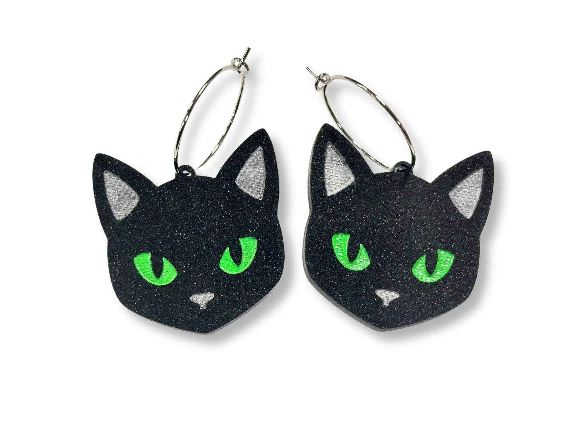 Black glitter cat face hoop earrings with bright green eyes on white background