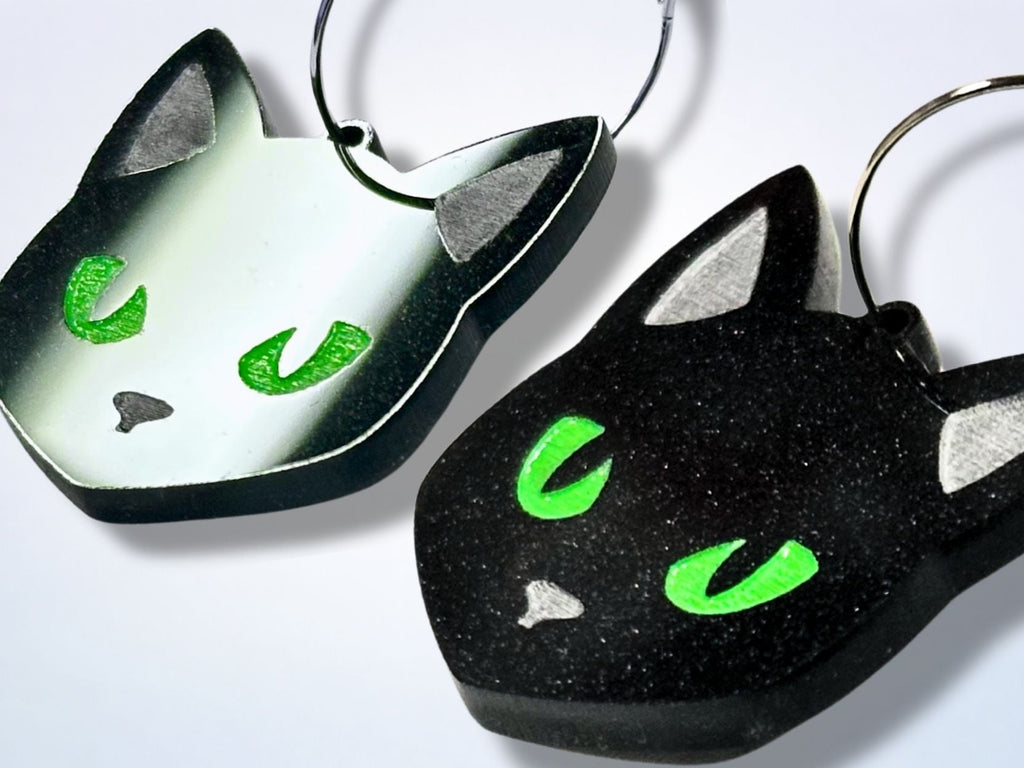 Close-up detail of black glitter cat earrings with neon green eyes and silver hoops