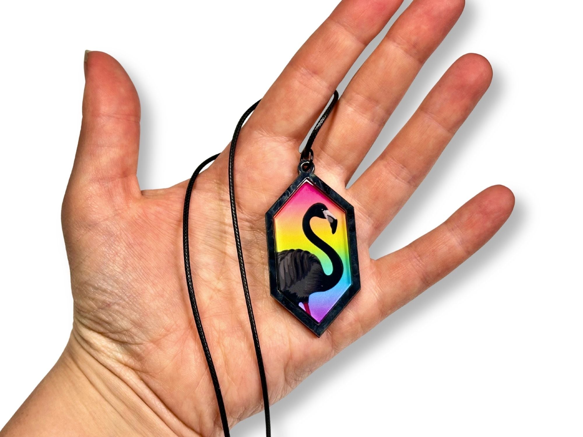 Scale reference of black flamingo hexagon pendant necklace shown in hand
