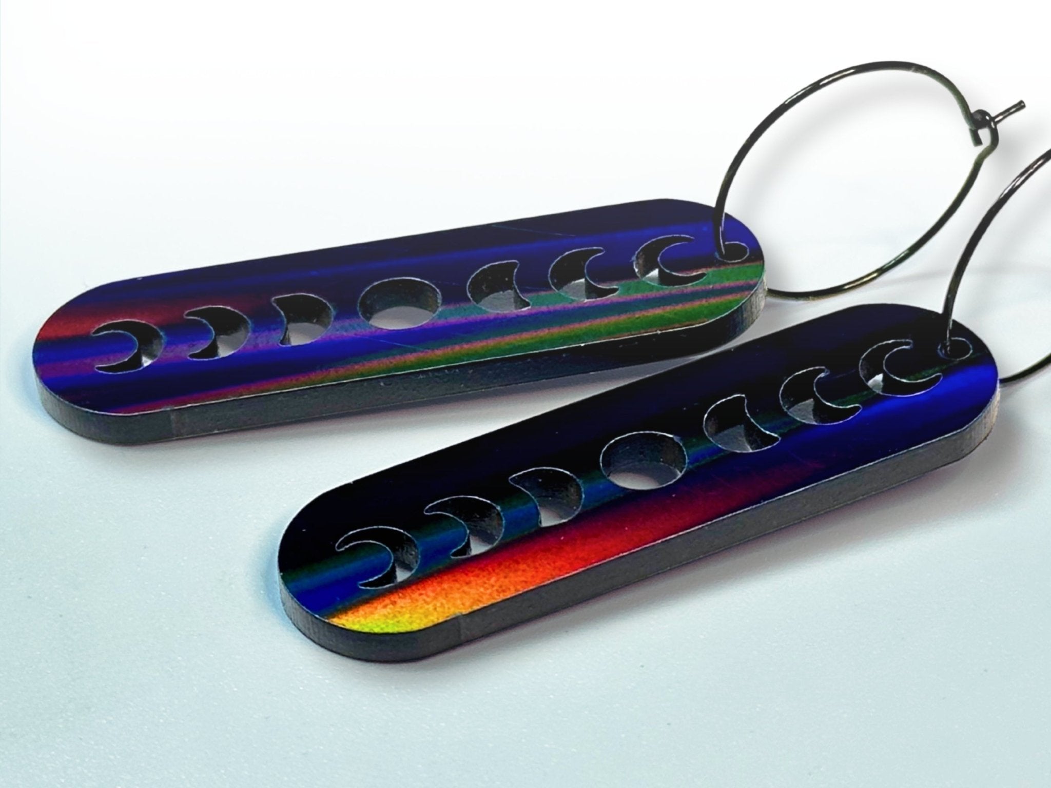Side view of Black Magic iridescent moon phase earrings showing color-shifting finish