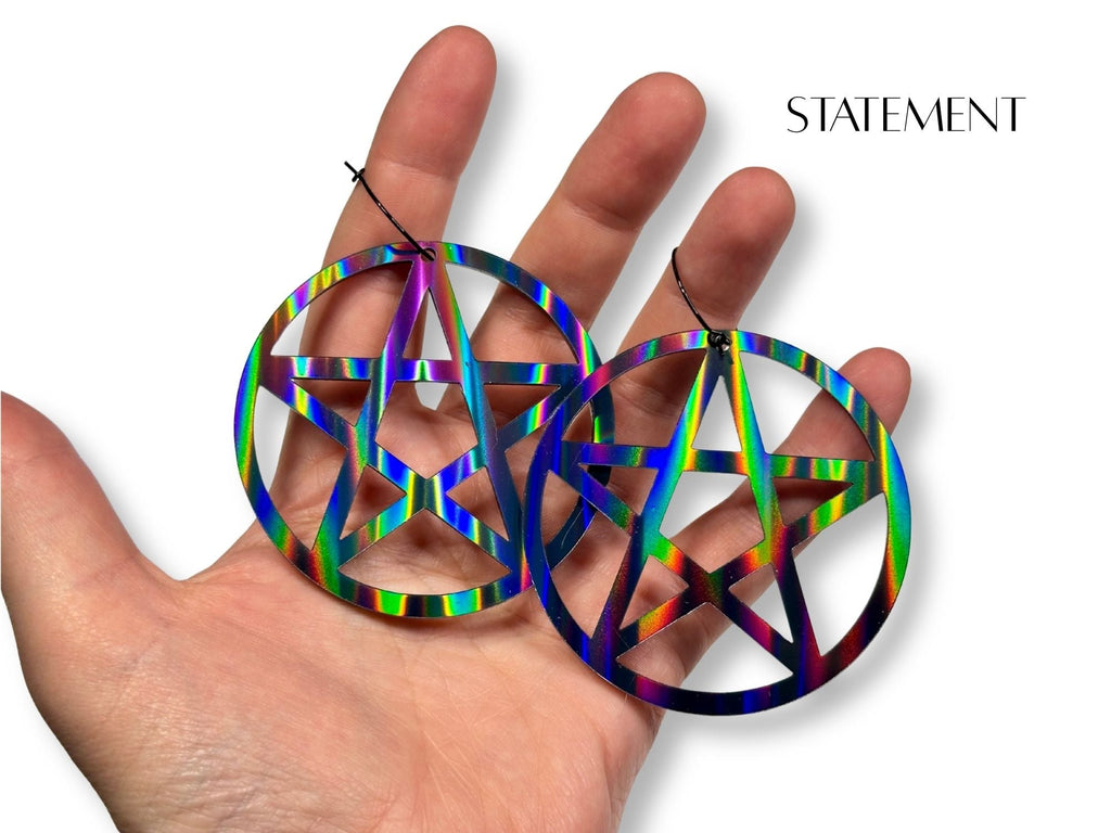 Statement size black rainbow pentagram earrings shown in hand for scale reference