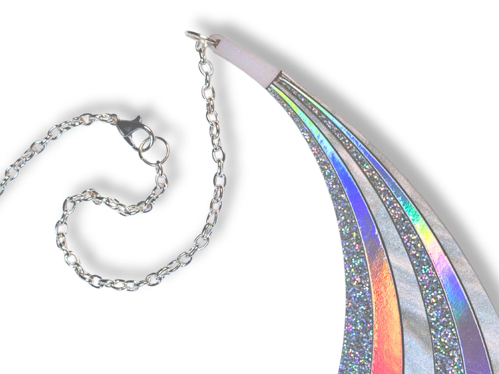 Disco Prism arc statement necklace with sweeping silver, holographic glitter, and iridescent rainbow layers on a white background. Detail of silver-toned chain and lobster clasp.