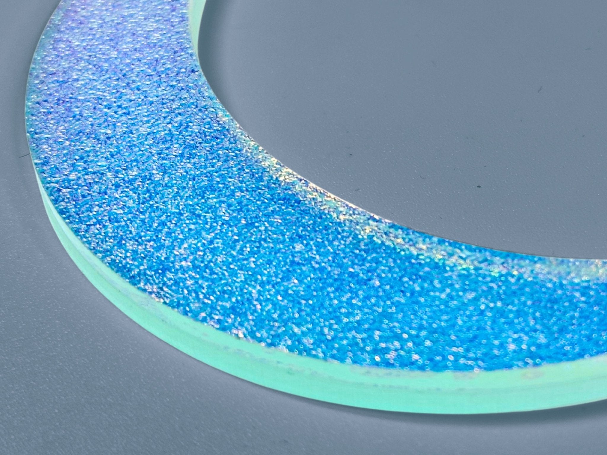 Close-up of blue iridescent textured crescent moon necklace 