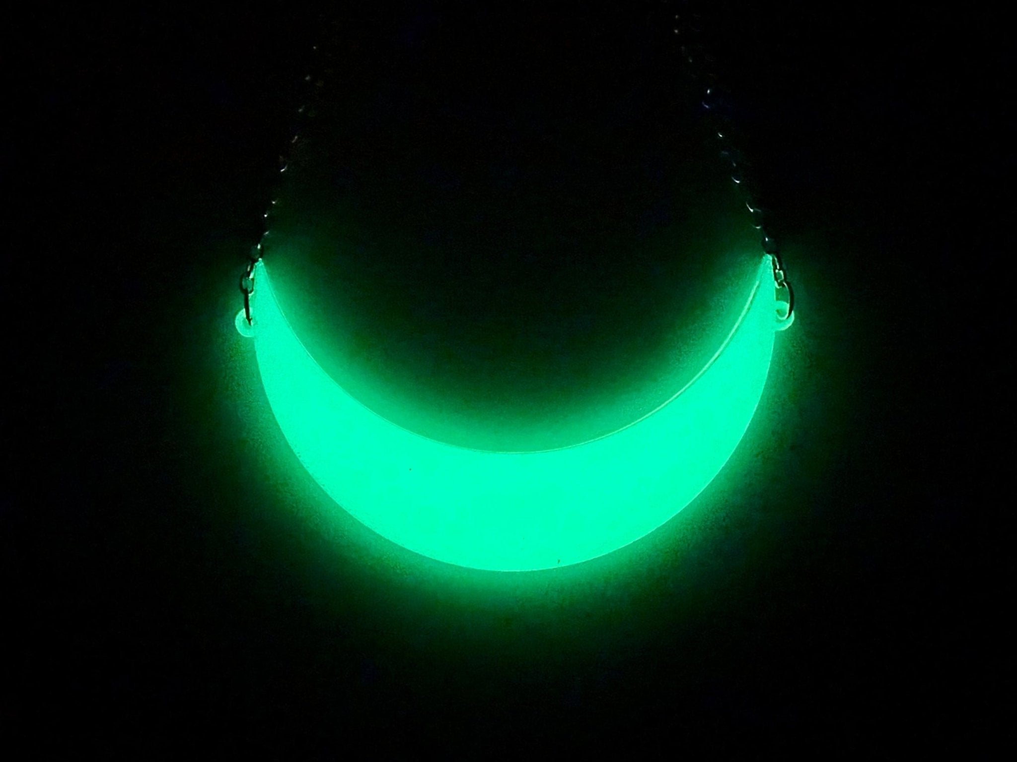 Crescent moon necklace glowing bright green in the dark