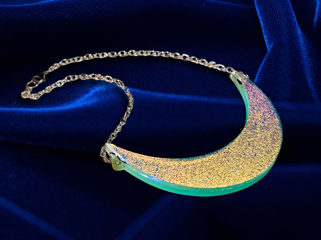 Iridescent crescent moon collar necklace displayed on deep blue velvet