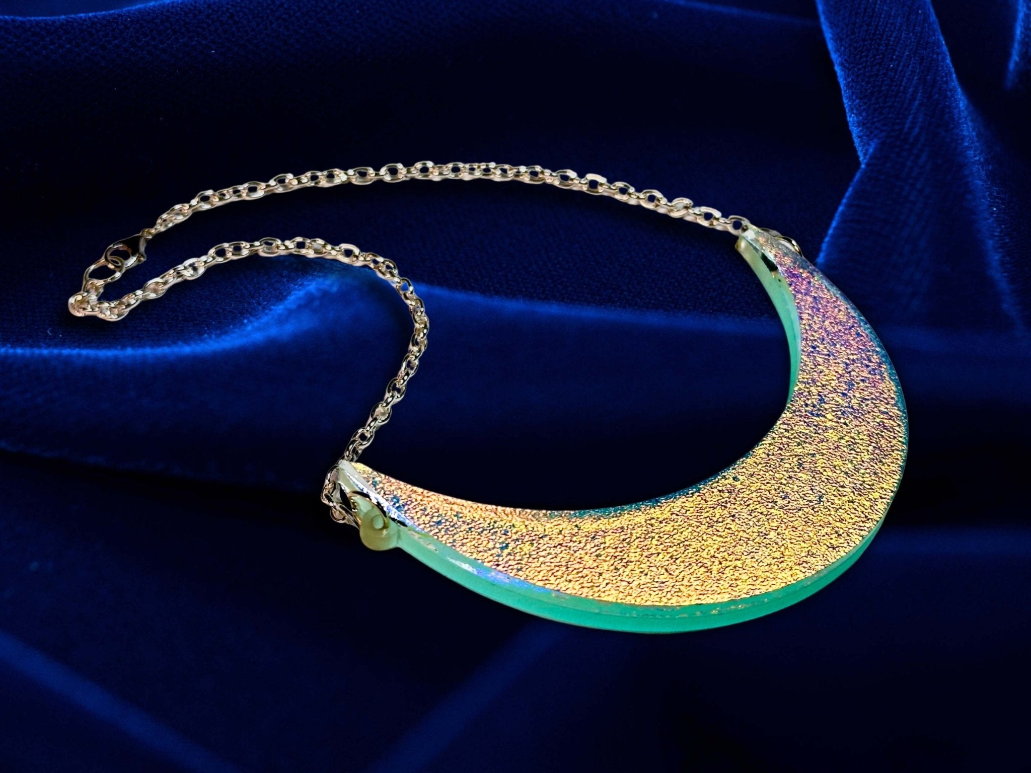 Iridescent crescent moon collar necklace displayed on deep blue velvet