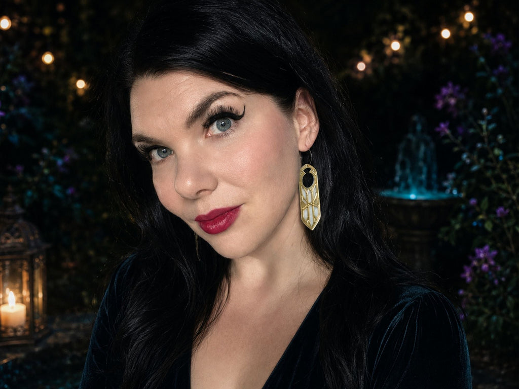 Model wearing gold mirror Disa fantasy statement earrings against dark atmospheric background