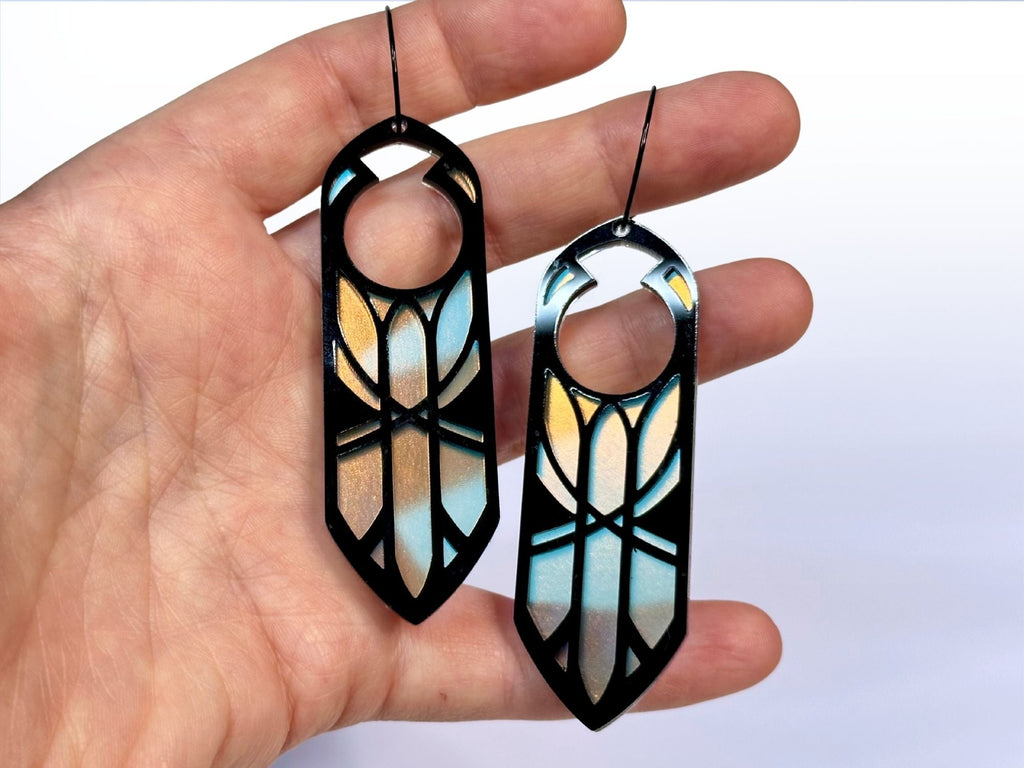 Hand holding black and iridescent Disa statement earrings for size reference