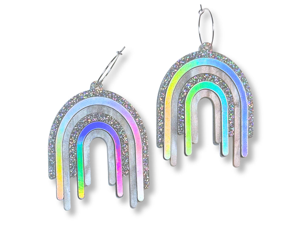 Disco Prism drip earrings with layered silver, holographic glitter, and iridescent rainbow arcs on a white background.