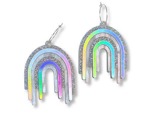 Disco Prism drip earrings with layered silver, holographic glitter, and iridescent rainbow arcs on a white background.