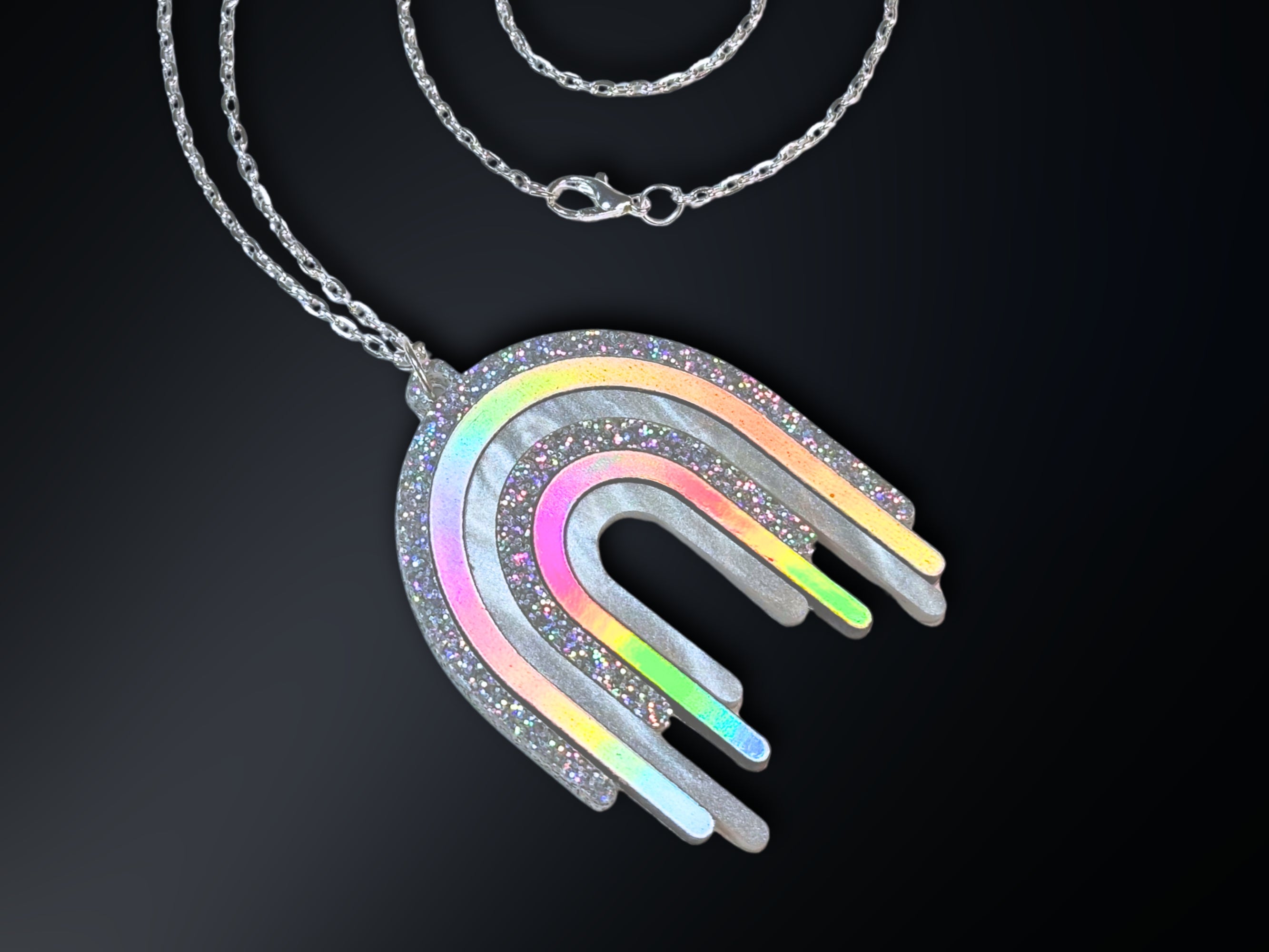 Disco Prism rainbow drip pendant necklace with layered silver, holographic glitter and iridescent arcs on a stainless steel chain.