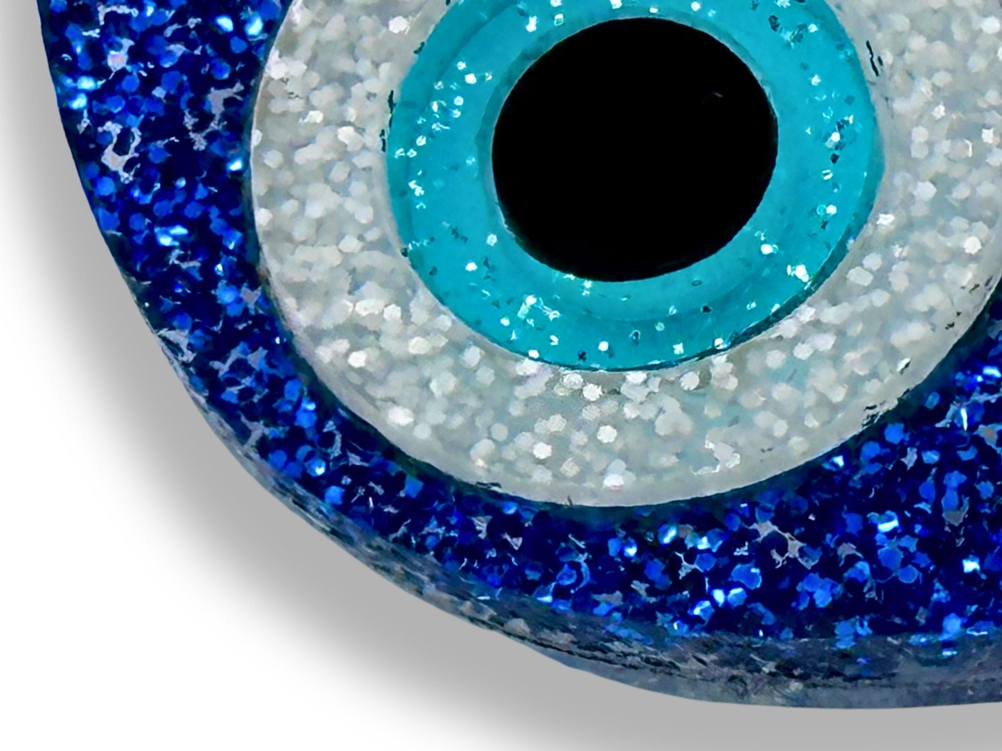 close up of evil eye statement earrings showing layered acrylic detail glitter and textured finishes blue white black macro