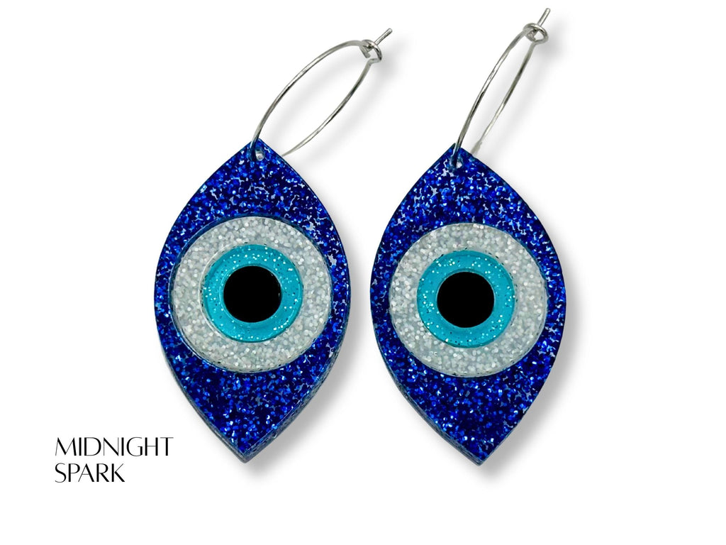 evil eye statement earrings styled flatlay glitter acrylic talisman jewelry mythic aesthetic blue white black