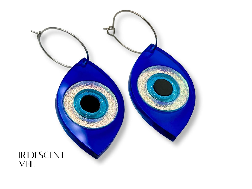 evil eye statement earrings styled flatlay iridescent acrylic talisman jewelry mythic aesthetic blue iridescent black