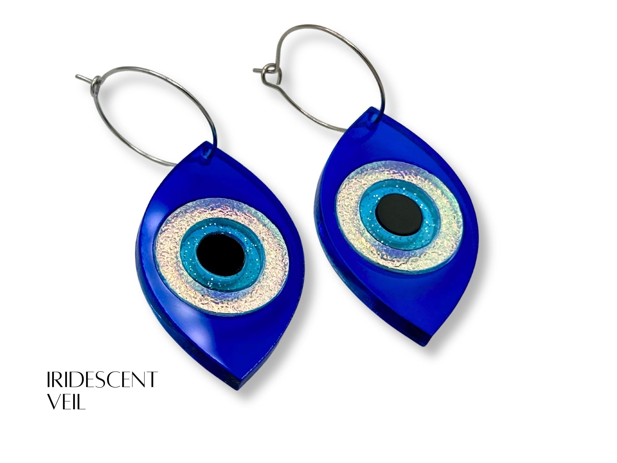 evil eye statement earrings styled flatlay iridescent acrylic talisman jewelry mythic aesthetic blue iridescent black