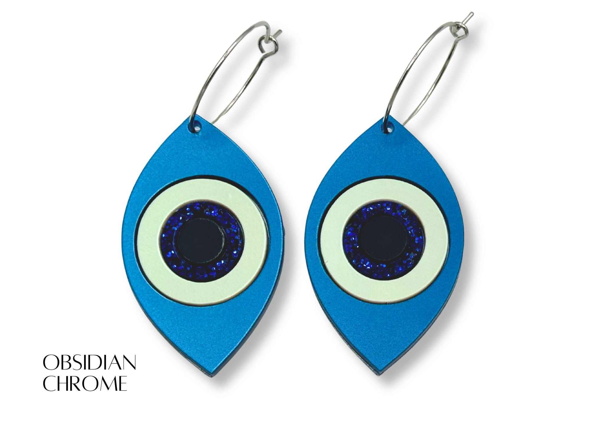 evil eye statement earrings styled flatlay metallic acrylic talisman jewelry mythic aesthetic blue white black