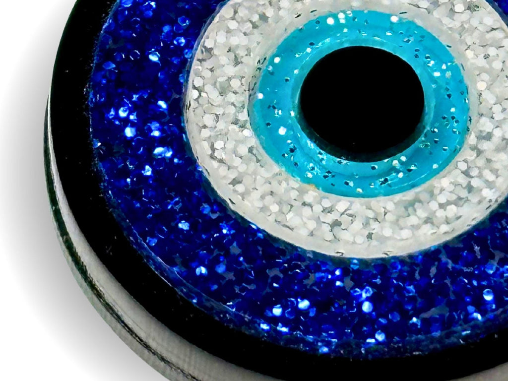 layered construction of glitter evil eye pendant necklace showing dimensional acrylic design detail macro close up blue white black