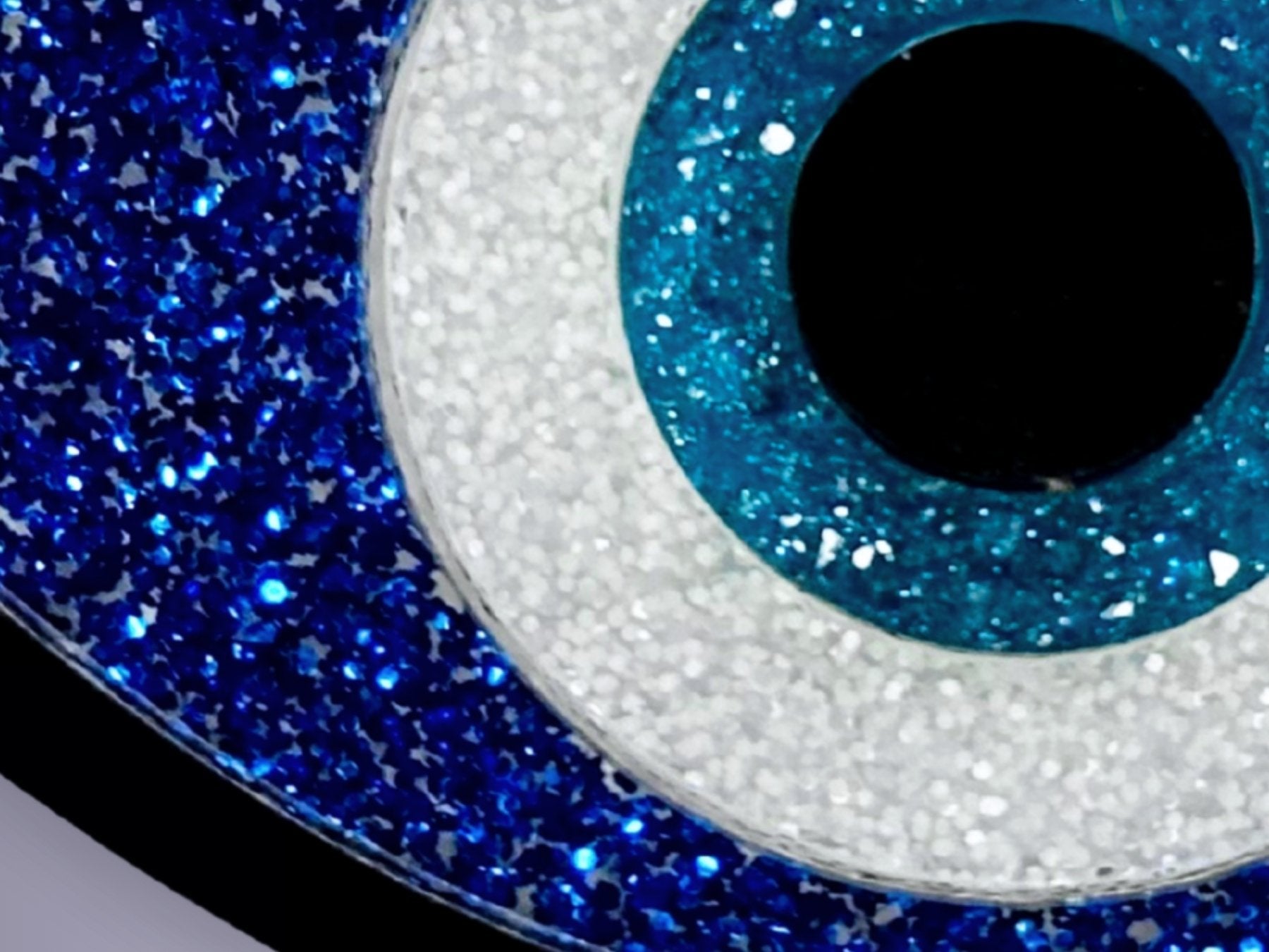 close up of evil eye necklace showing glitter acrylic detail layered construction and reflective surface and resin druzy crystal