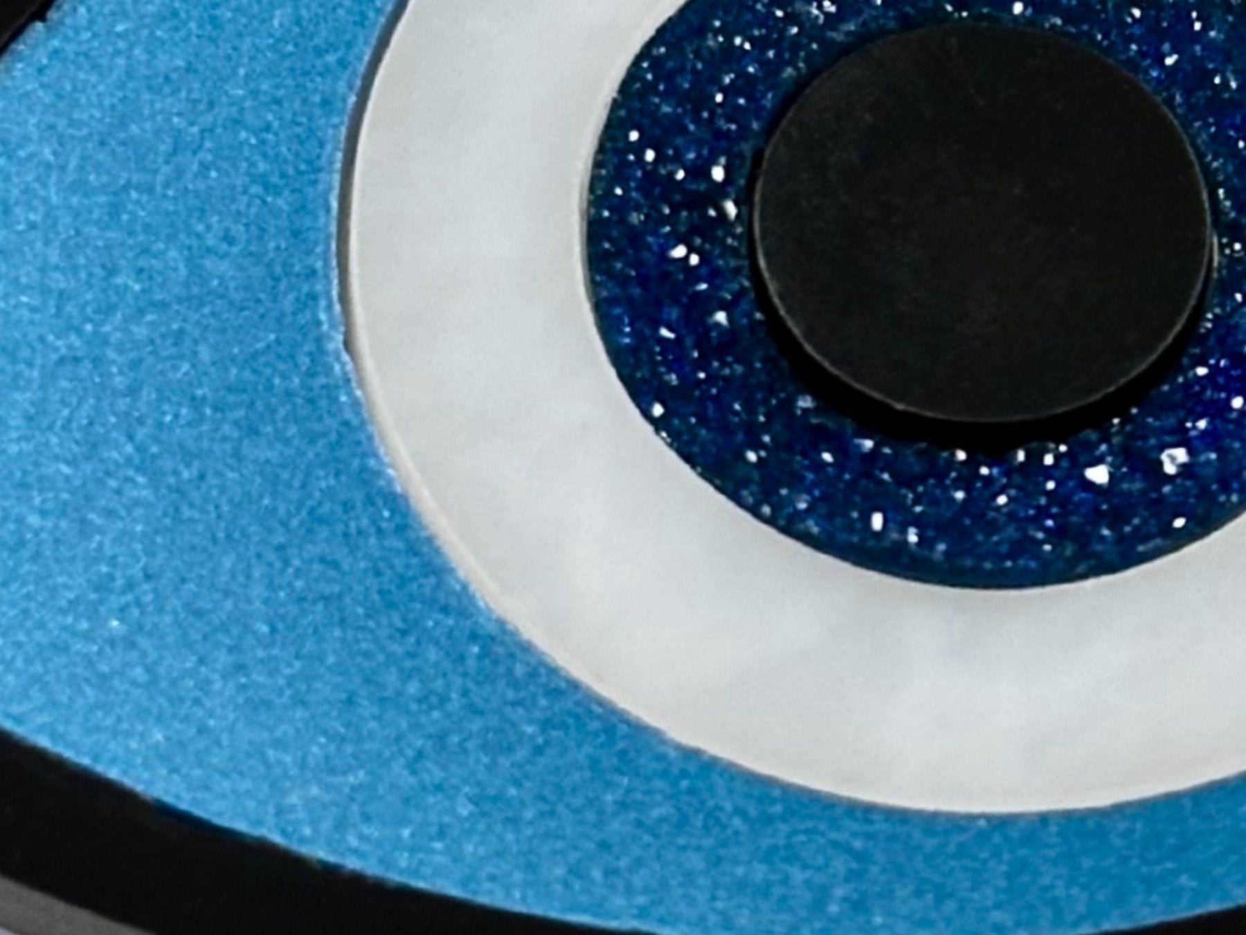 close up of evil eye necklace showing metallic acrylic detail layered construction and resin druzy crystal