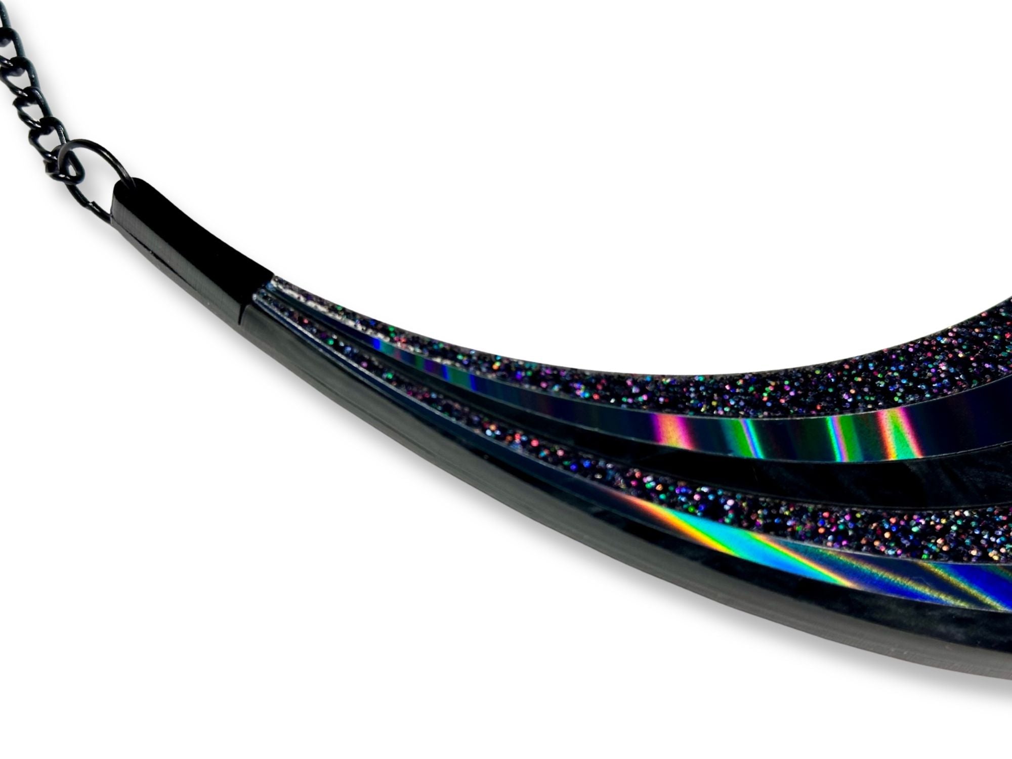 Close-up detail of holographic and iridescent black acrylic layers of rainbow arc statement necklace