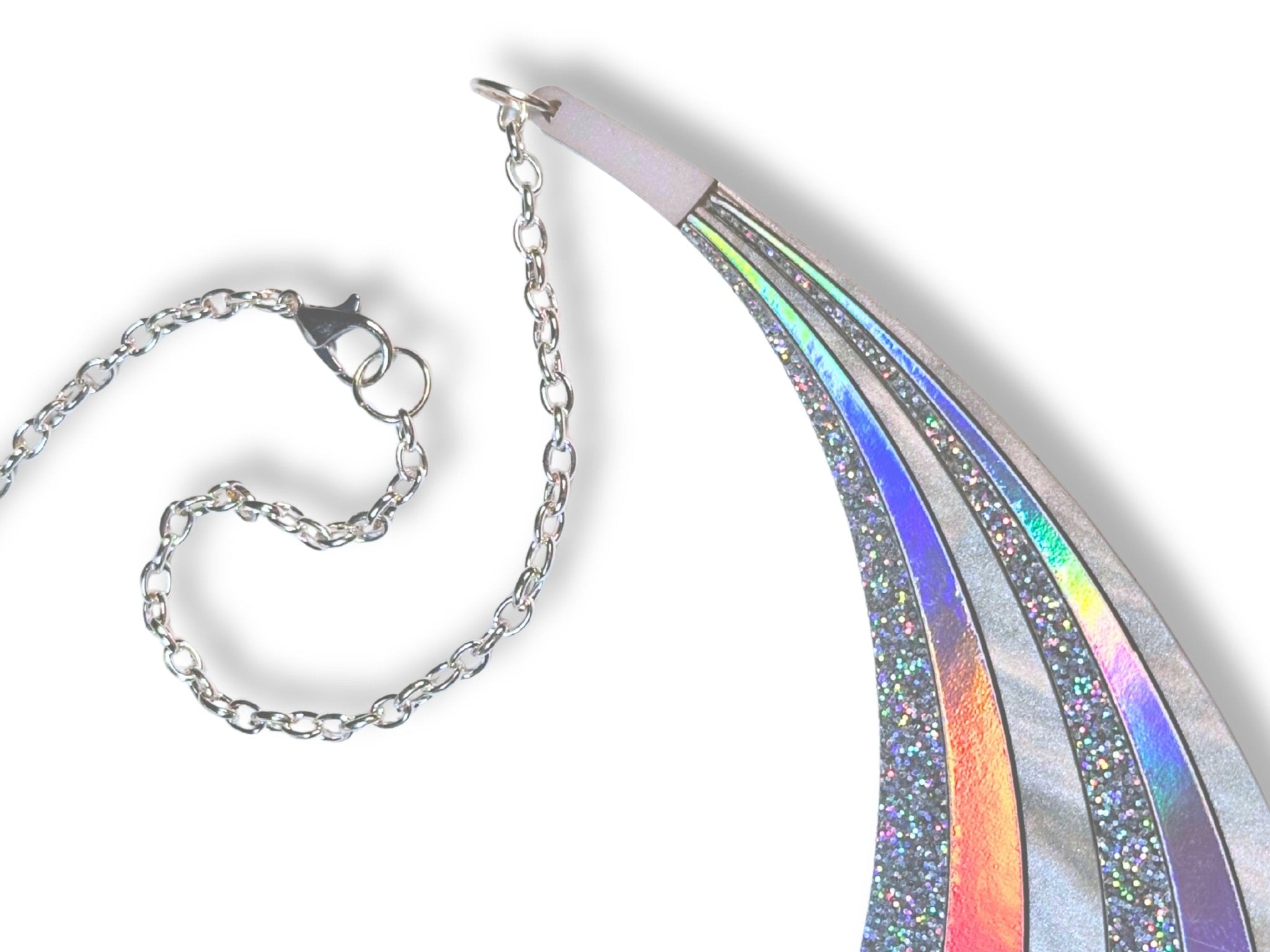 Disco Prism arc statement necklace with sweeping silver, holographic glitter, and iridescent rainbow layers on a white background. Detail of silver-toned chain and lobster clasp.