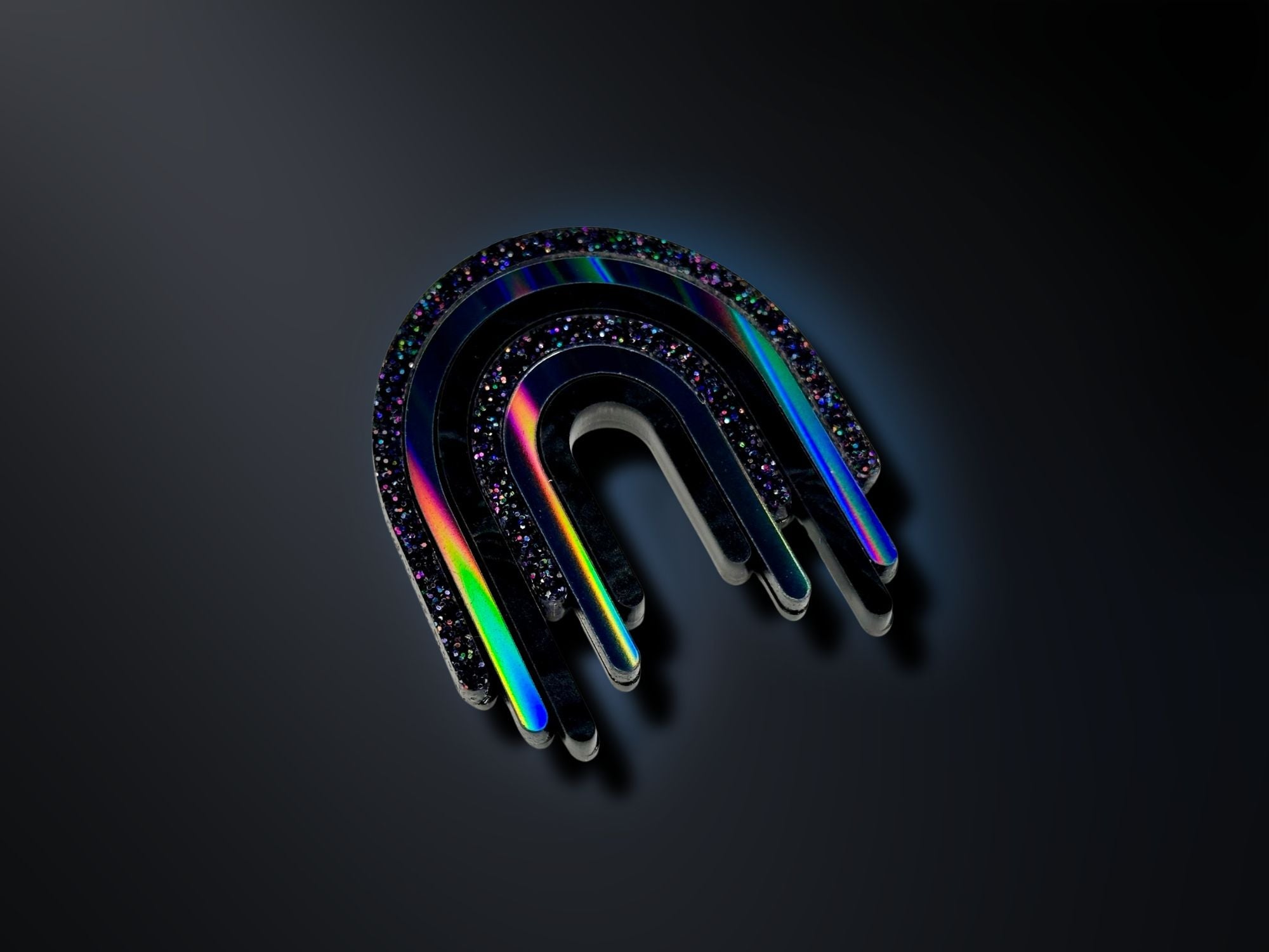 Black rainbow acrylic drip brooch photographed on dark background