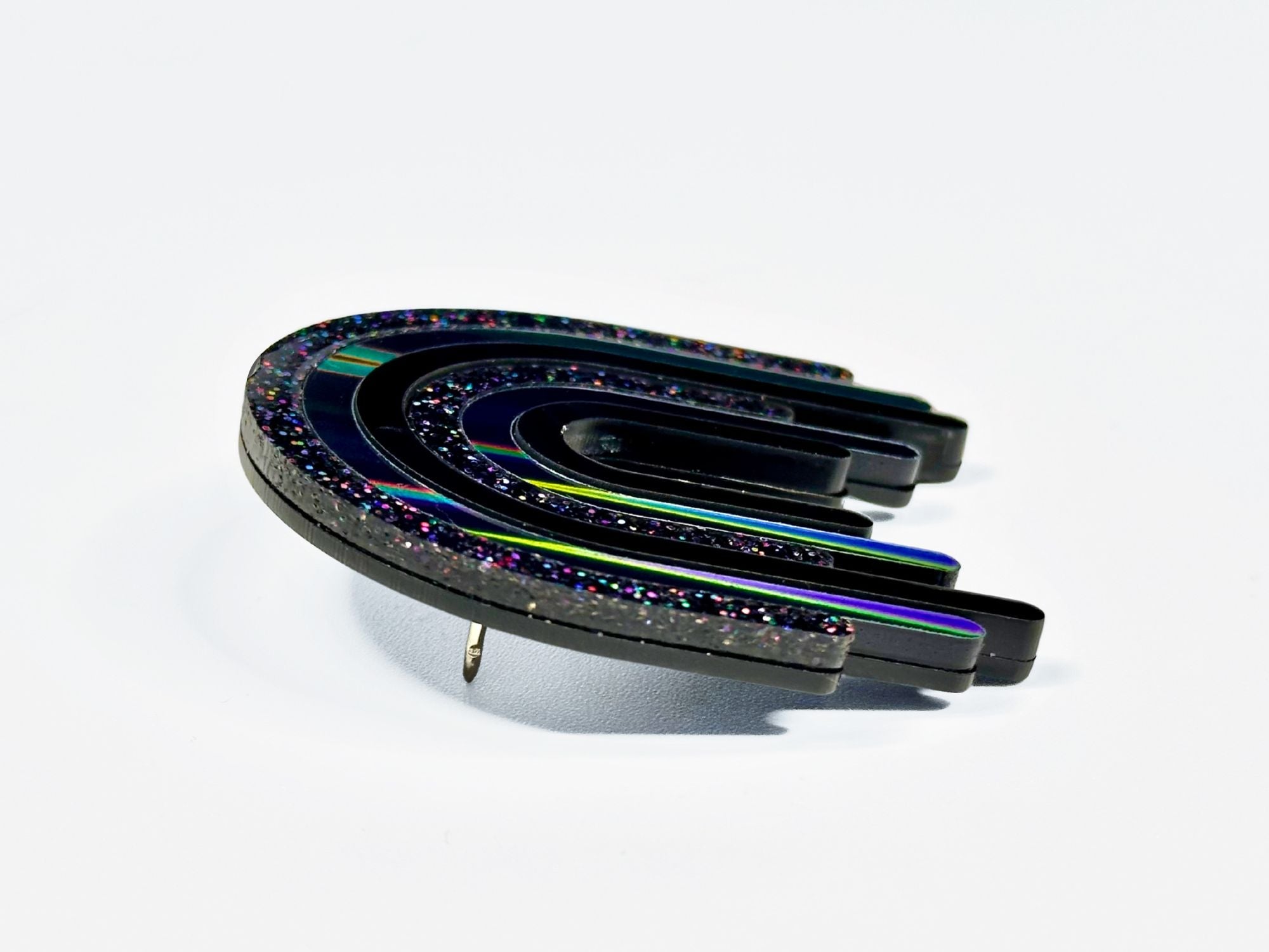 Side angle view of layered black rainbow acrylic brooch