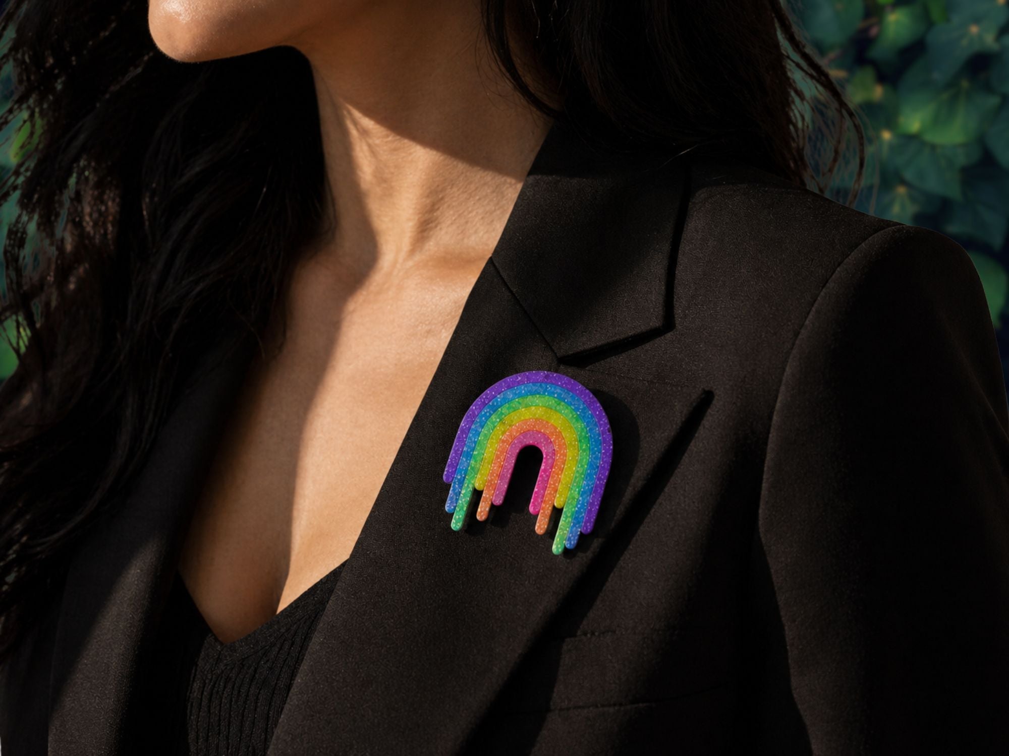 Model wearing Full Spectrum Rebel Rainbow Rave drip brooch on black blazer lapel.