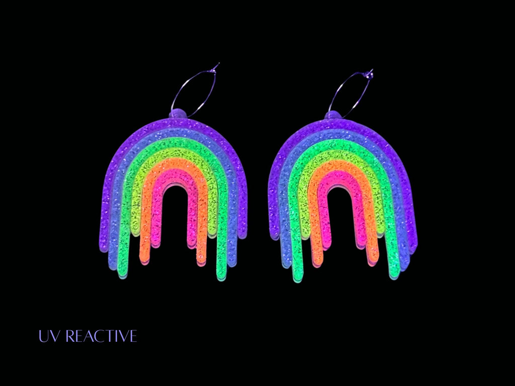 UV reactive Full Spectrum Rebel Rainbow Rave glitter rainbow drip earrings product editorial image on black background.