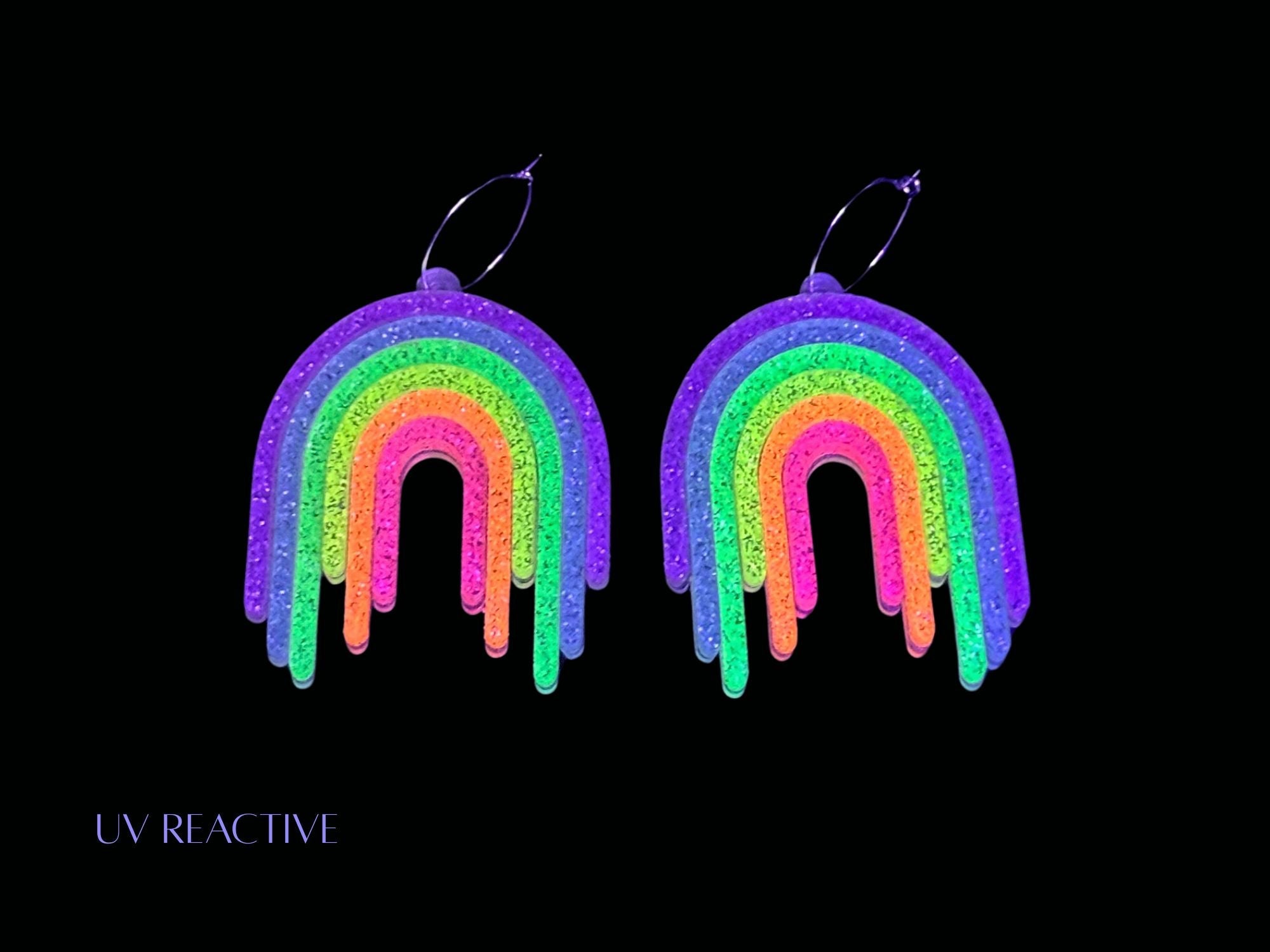 UV reactive Full Spectrum Rebel Rainbow Rave glitter rainbow drip earrings product editorial image on black background.