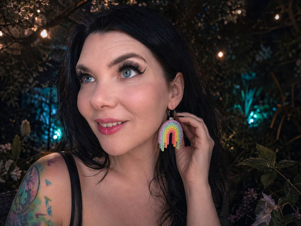 Model wearing Full Spectrum Rebel Rainbow Rave rainbow drip earrings in glitter acrylic.