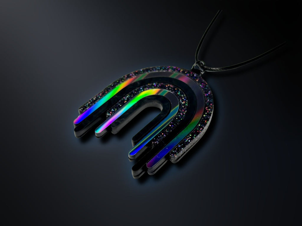 Black rainbow acrylic drip pendant photographed on dark background