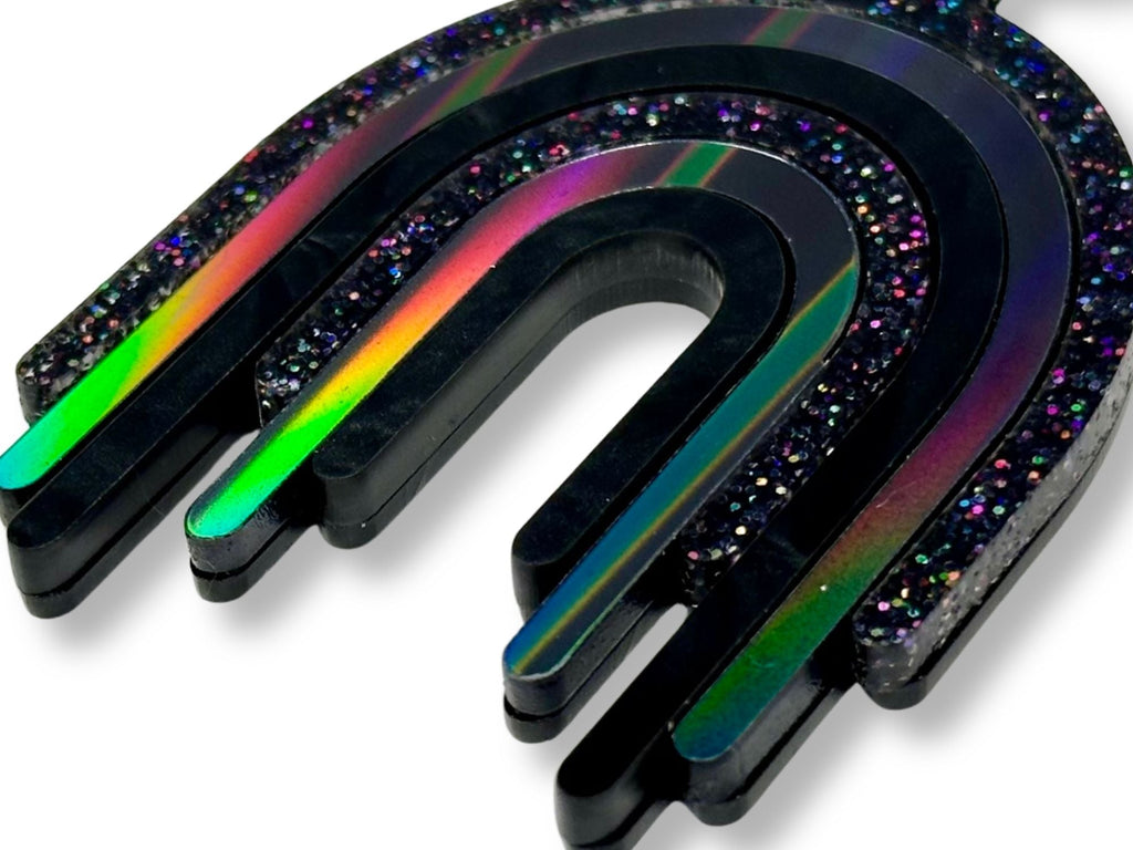 Close-up detail of holographic glitter and iridescent black acrylic layers on rainbow drip pendant