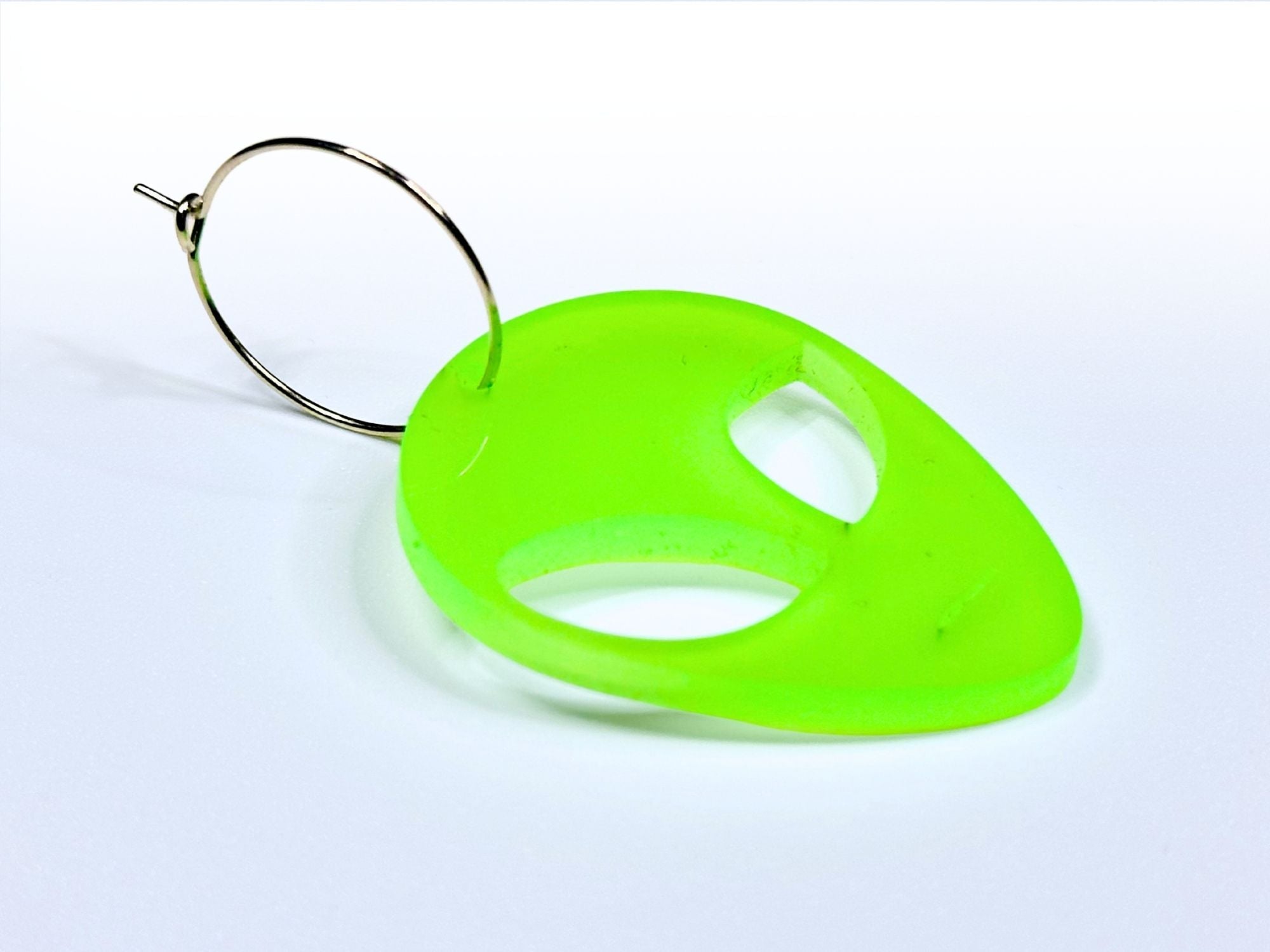 Close-up detail of neon green glow in the dark alien earring with silver hoop ear wire.