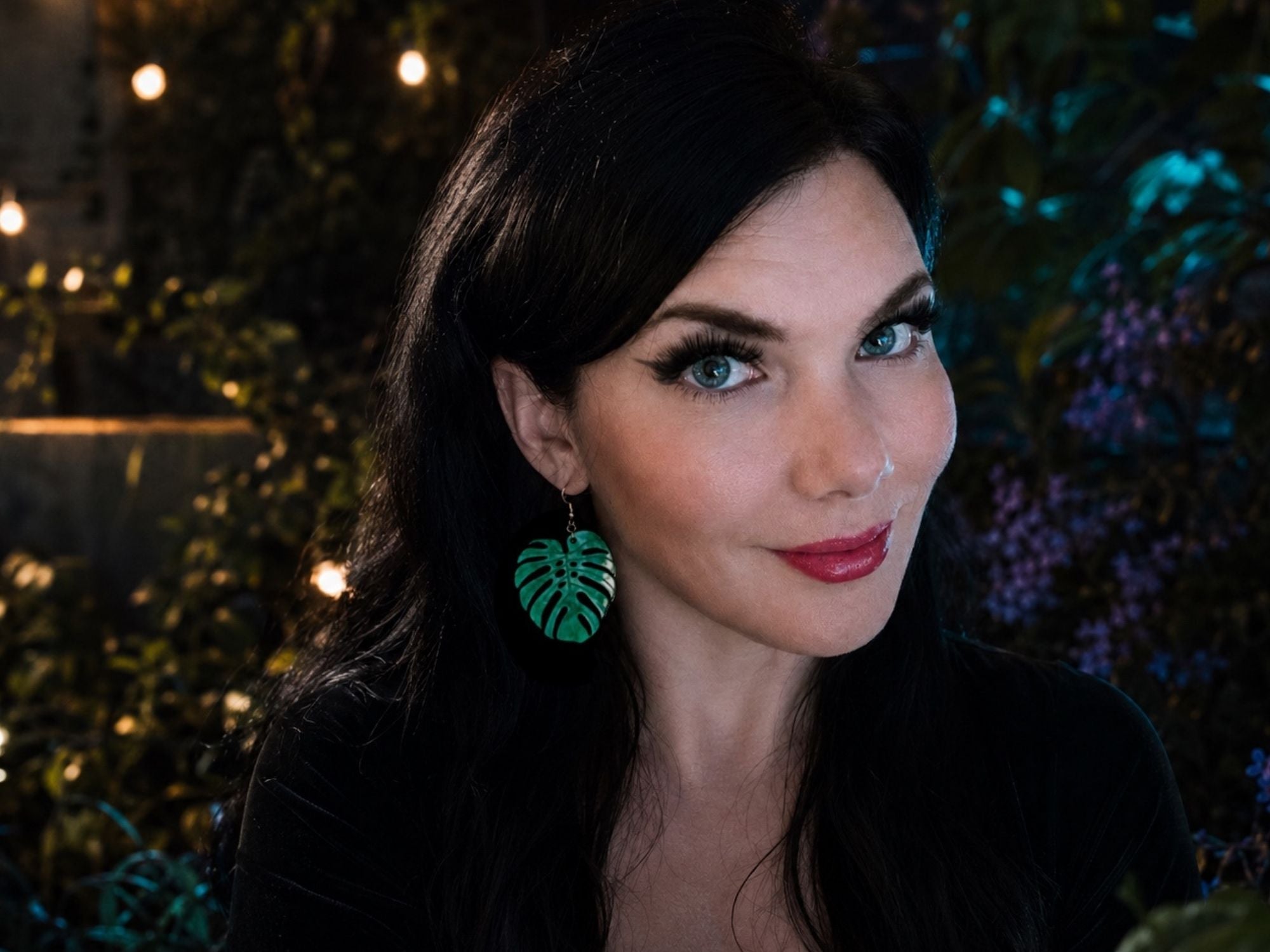 Woman wearing Verdant Pearl monstera leaf statement earrings for size reference and styling inspiration.