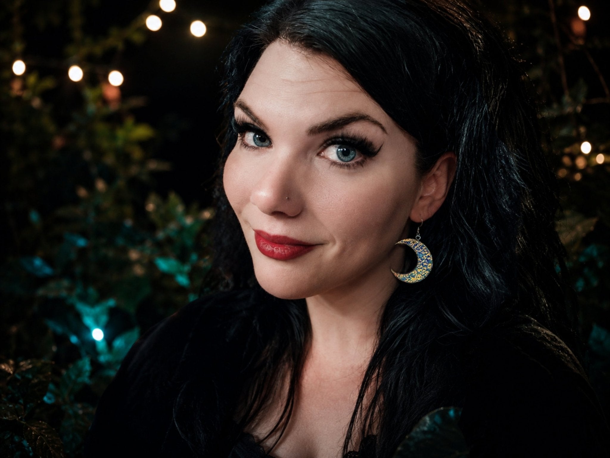 Model wearing textured iridescent crescent moon earrings with blue reflective finish.