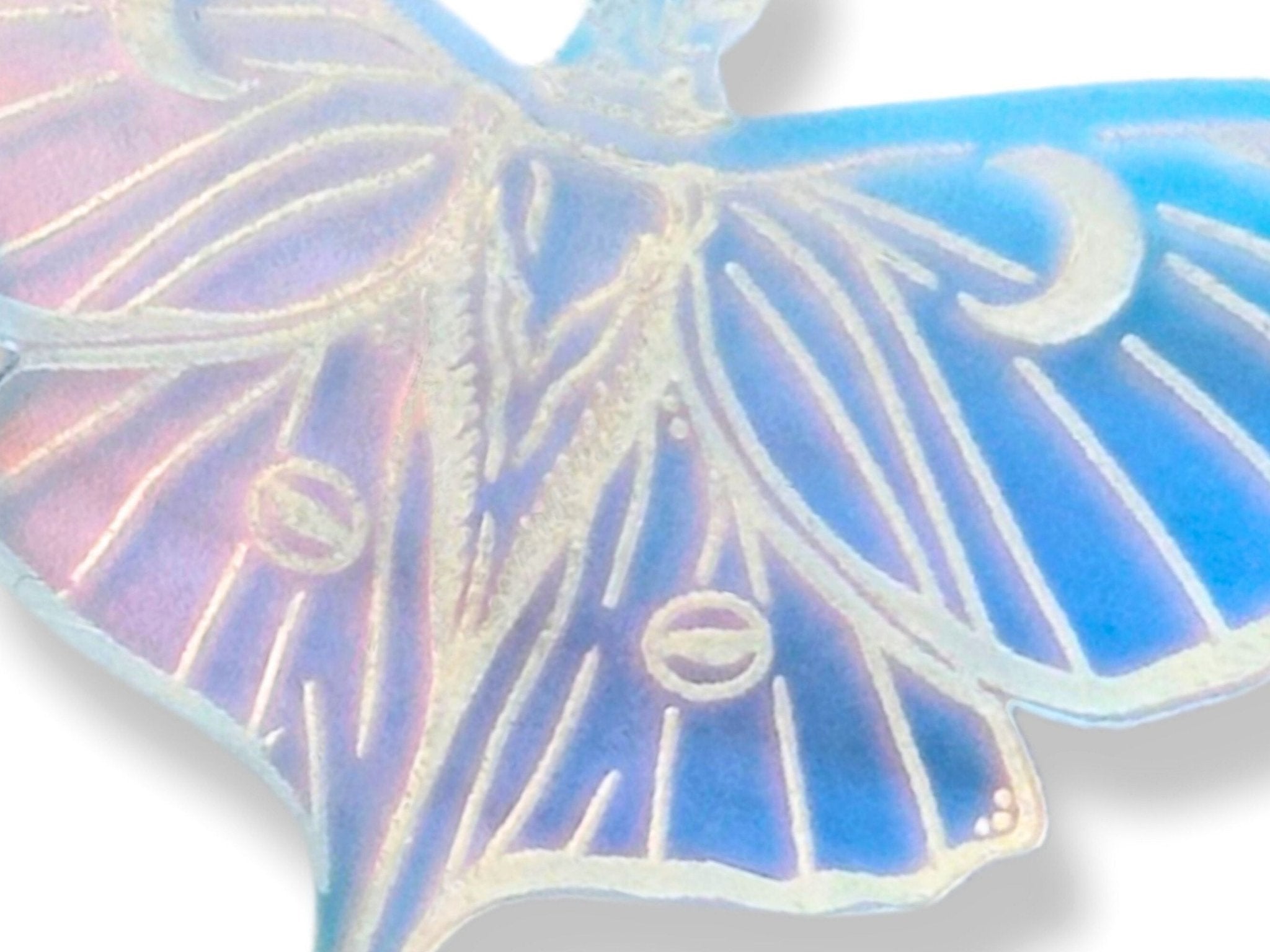 Close-up macro view of an iridescent Luna moth wing showing the engraved line details and luminous blue, lavender, and gold color shift.