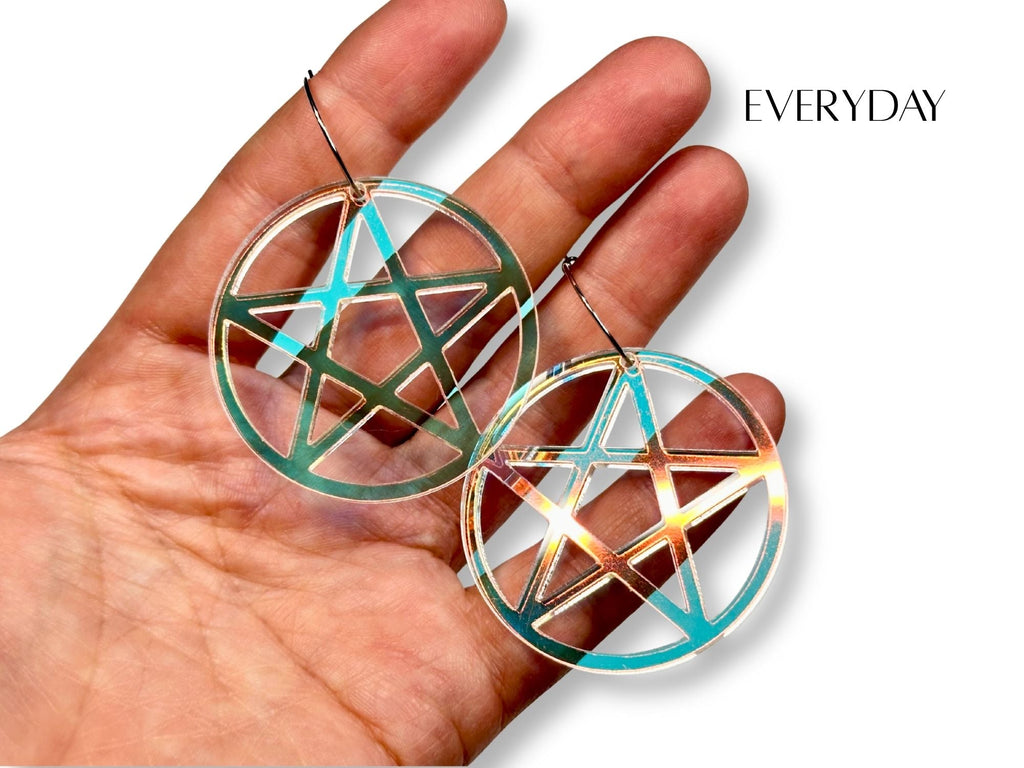 Everyday size iridescent pentagram earrings shown in hand for scale reference