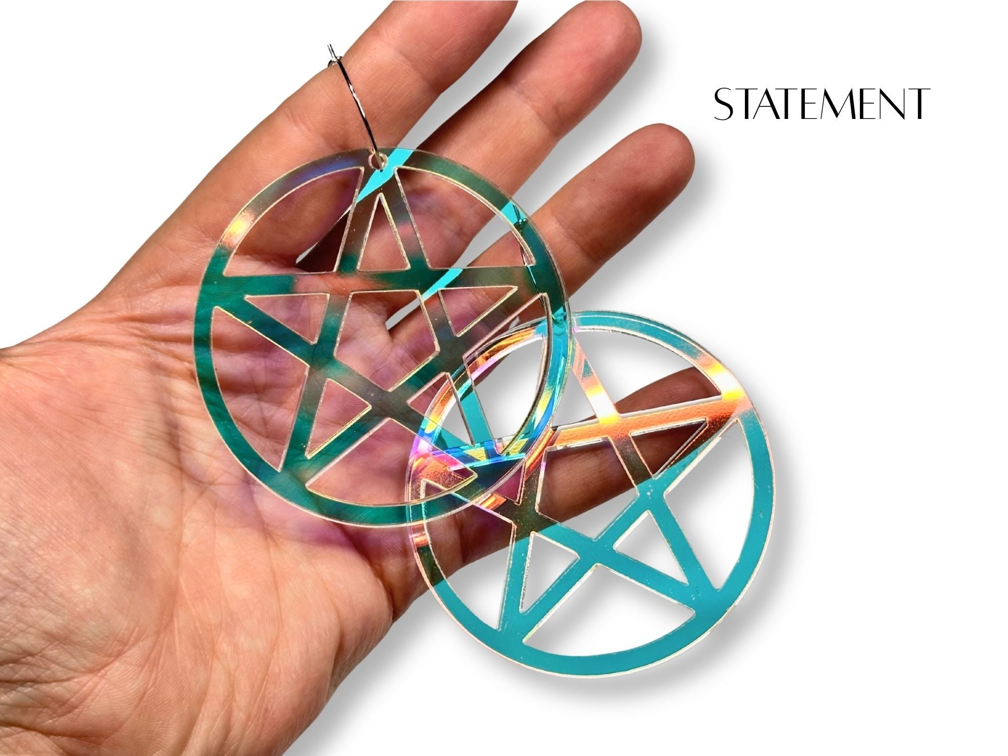 Statement size iridescent pentagram earrings shown in hand for scale reference