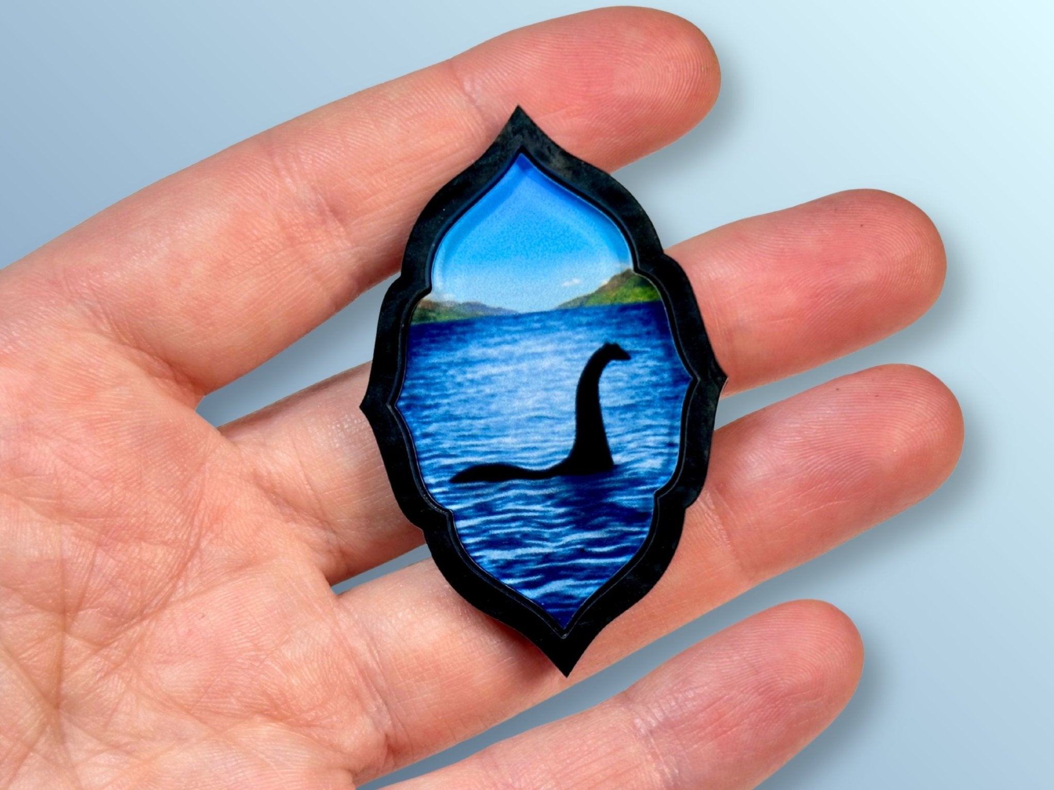 Loch Ness Monster brooch shown in hand for size reference.