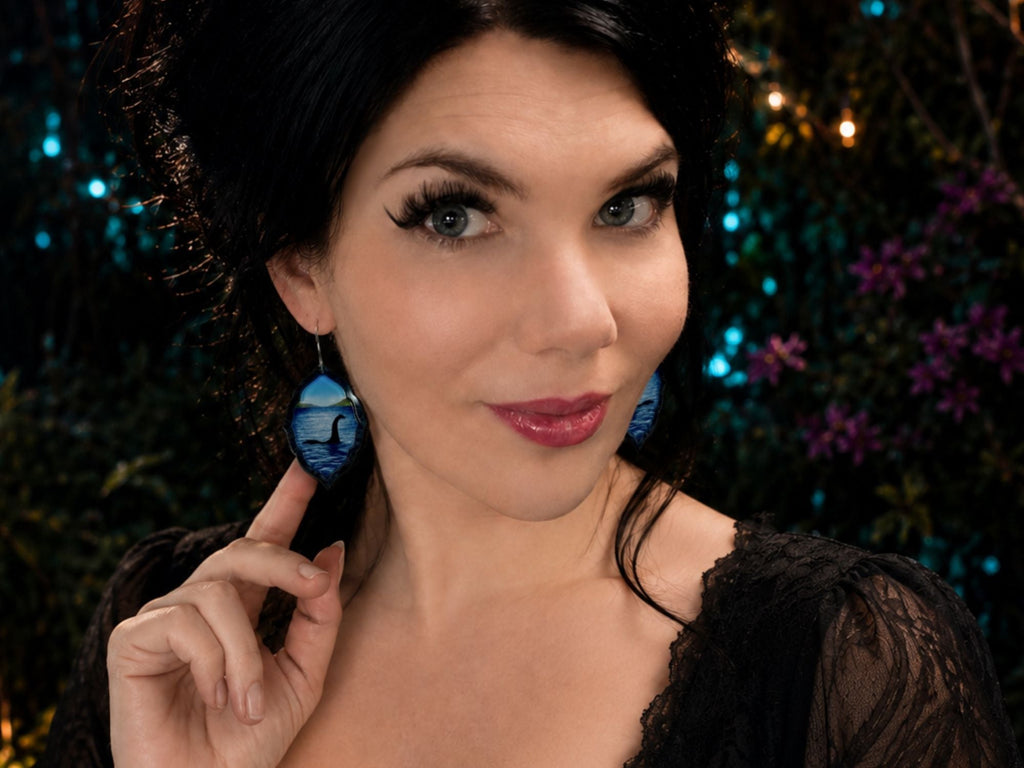 Model wearing Loch Ness monster lake scene earrings in layered acrylic.