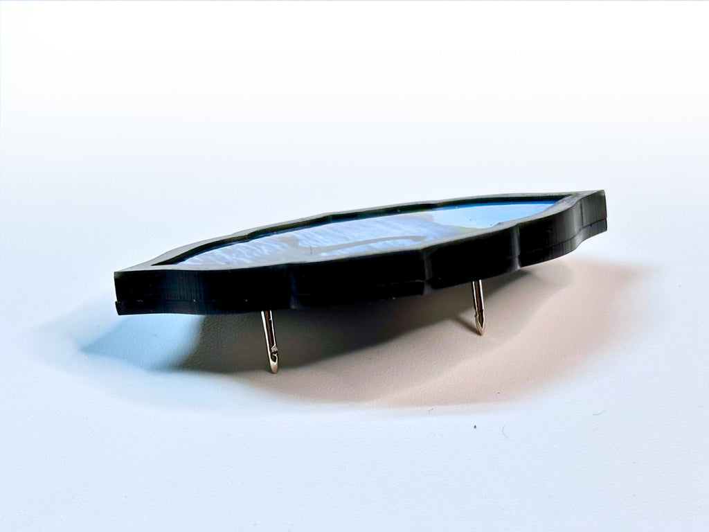 Side profile of layered acrylic Loch Ness Monster brooch showing its thickness and pin construction.