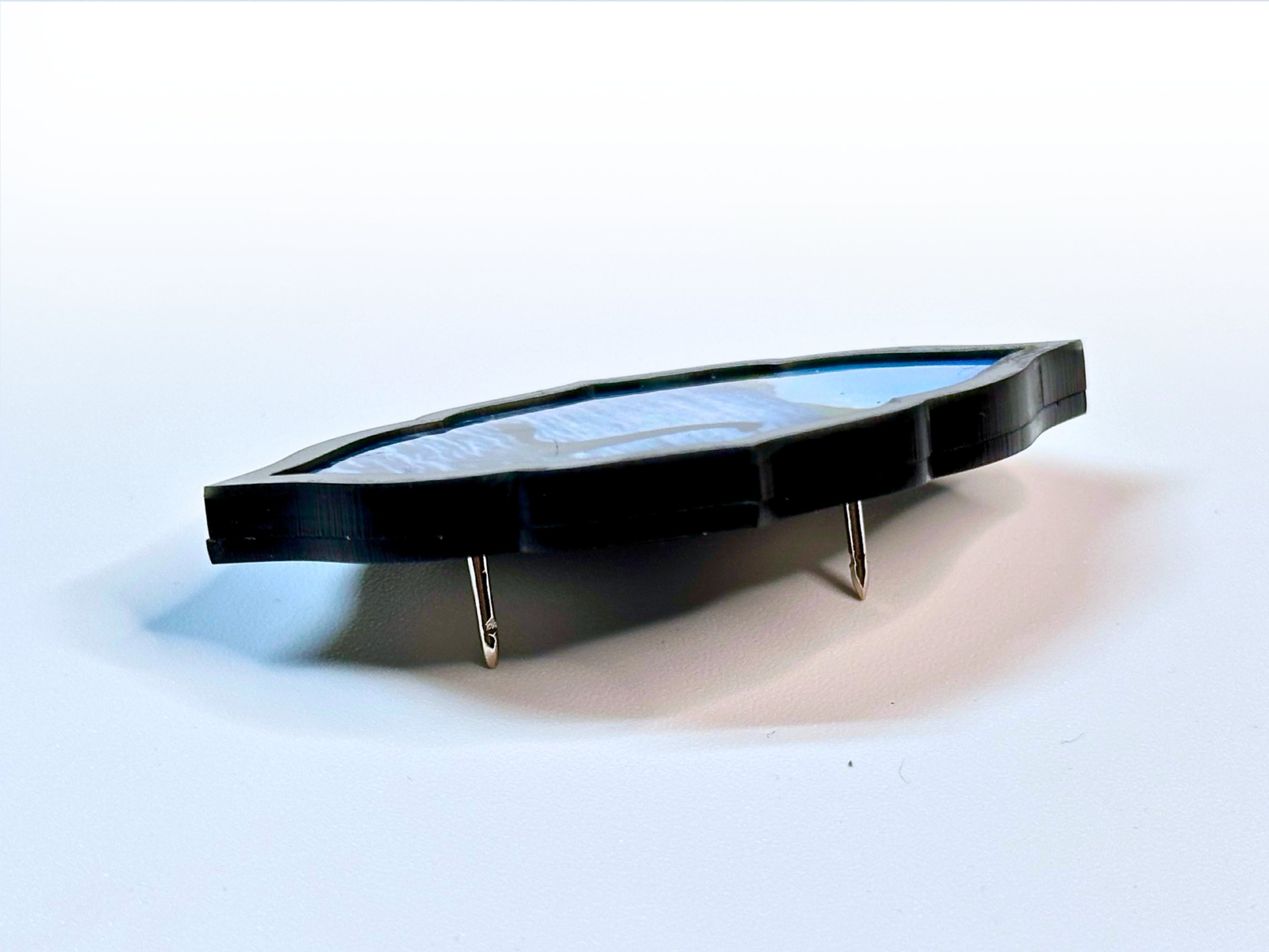 Side profile of layered acrylic Loch Ness Monster brooch showing its thickness and pin construction.