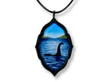 Loch Ness Monster acrylic pendant hanging from a black faux leather cord on a white background.