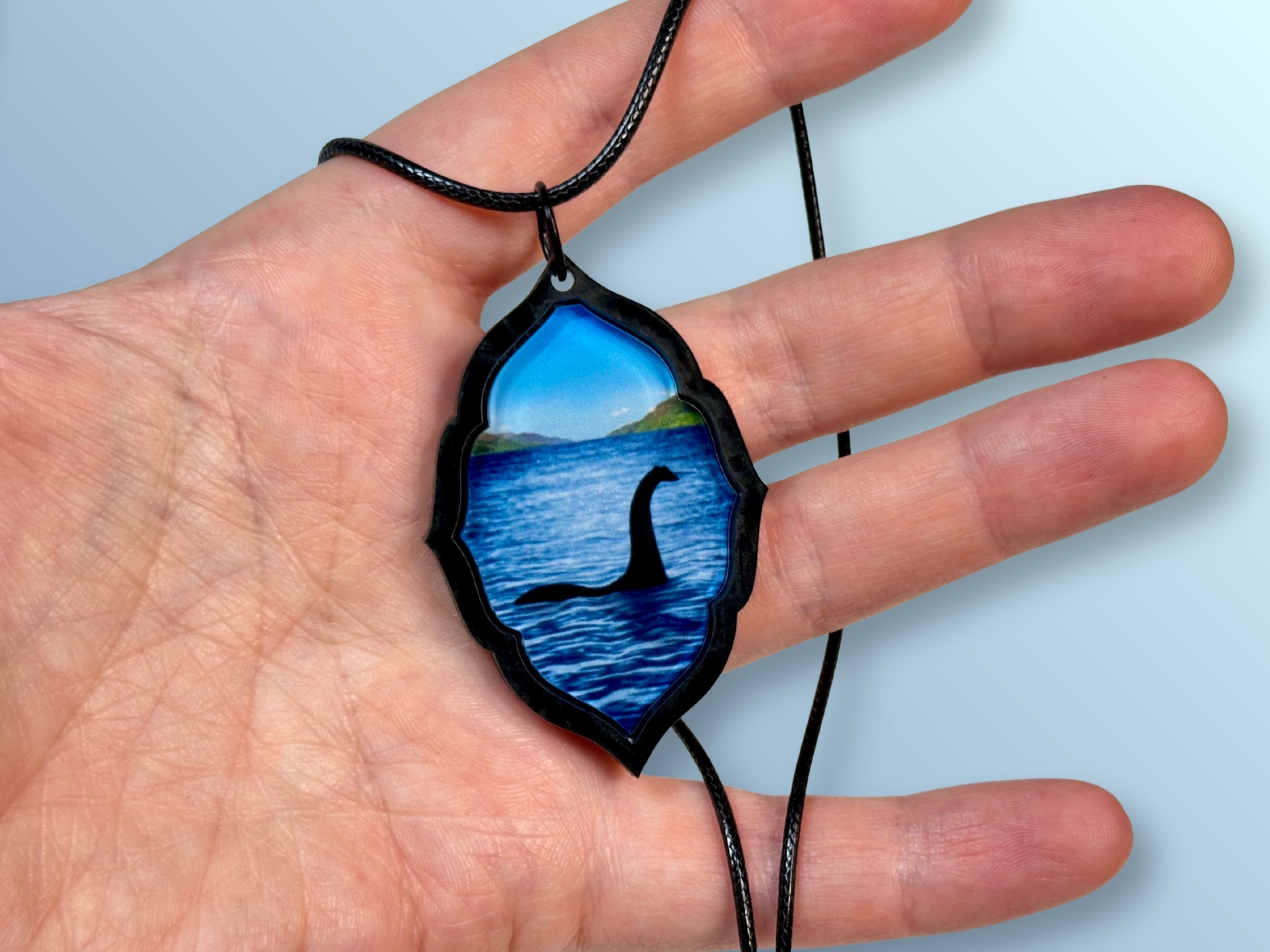 Loch Ness Monster pendant shown in hand for size reference.
