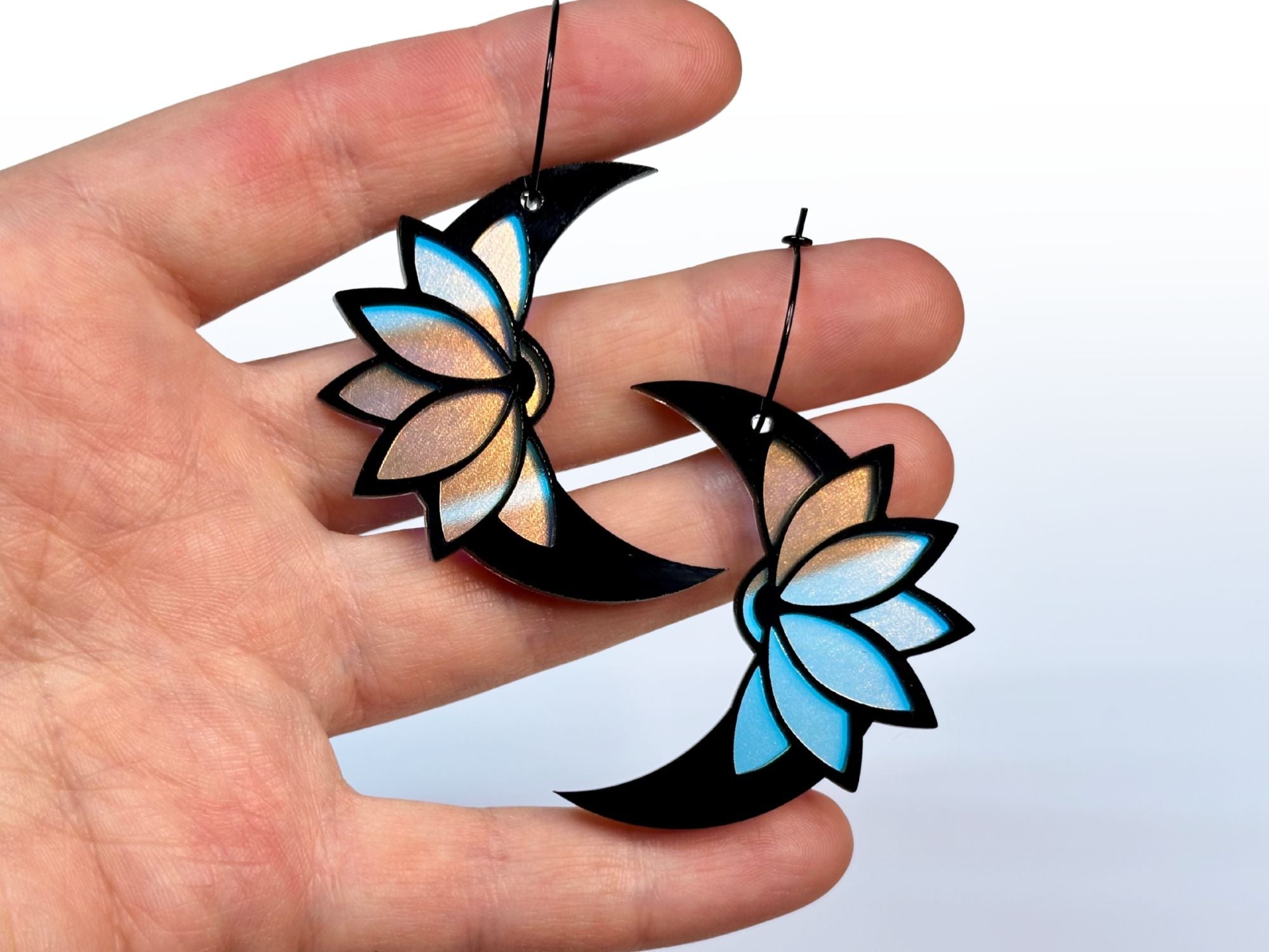 Hand holding Obsidian lotus moon earrings showing size and scale
