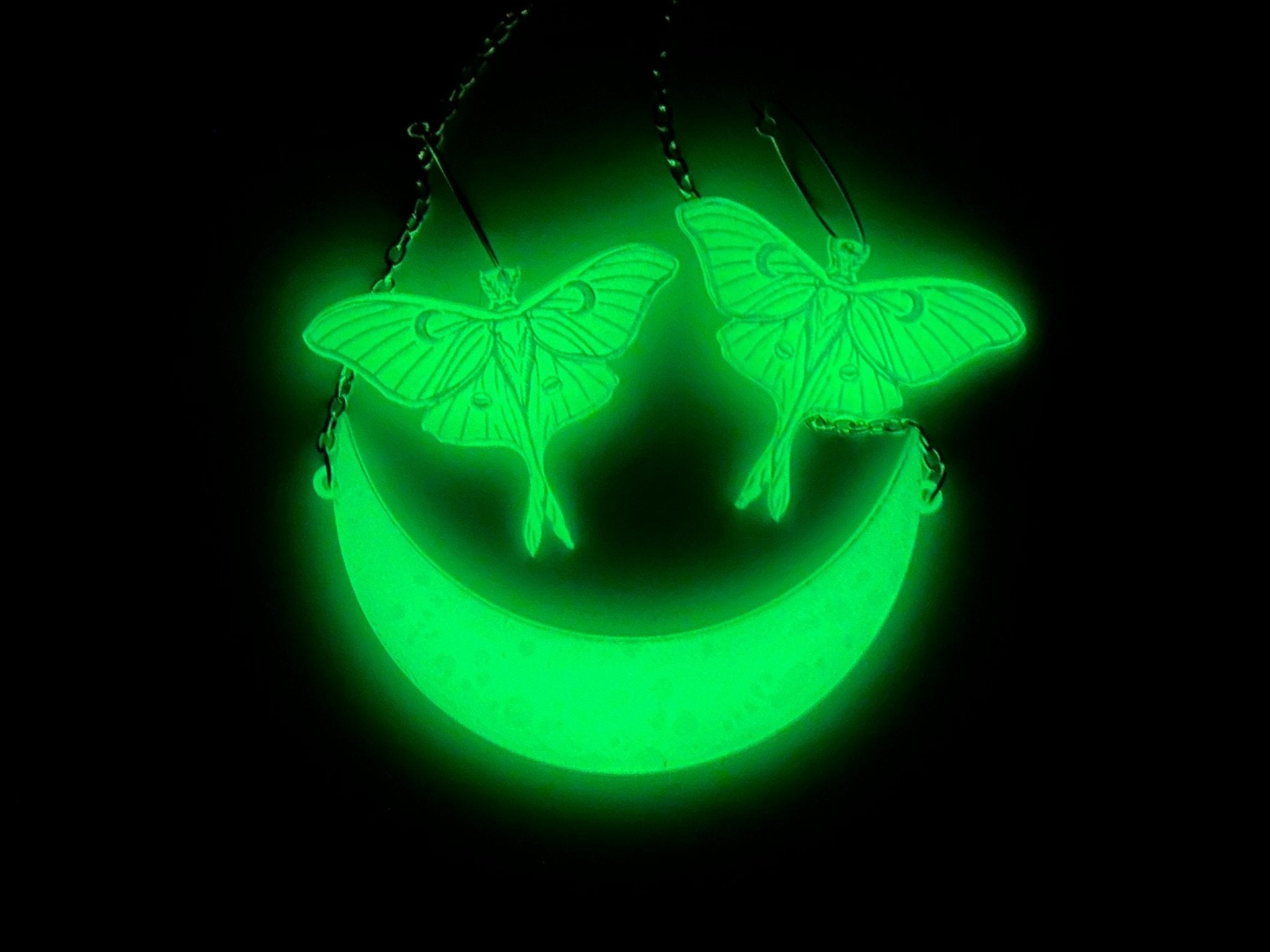 Luna moth earrings and crescent moon necklace glowing bright green in the dark